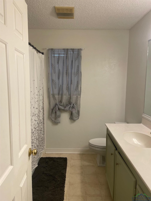 bathroom with tile patterned flooring, vanity, a textured ceiling, and toilet