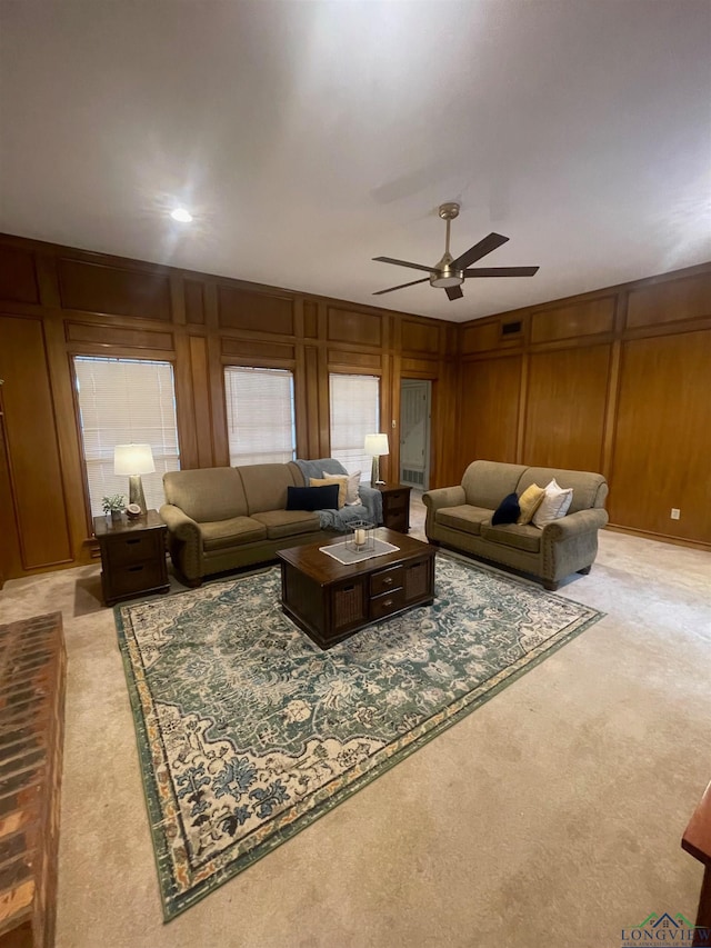 carpeted living room with ceiling fan and wooden walls