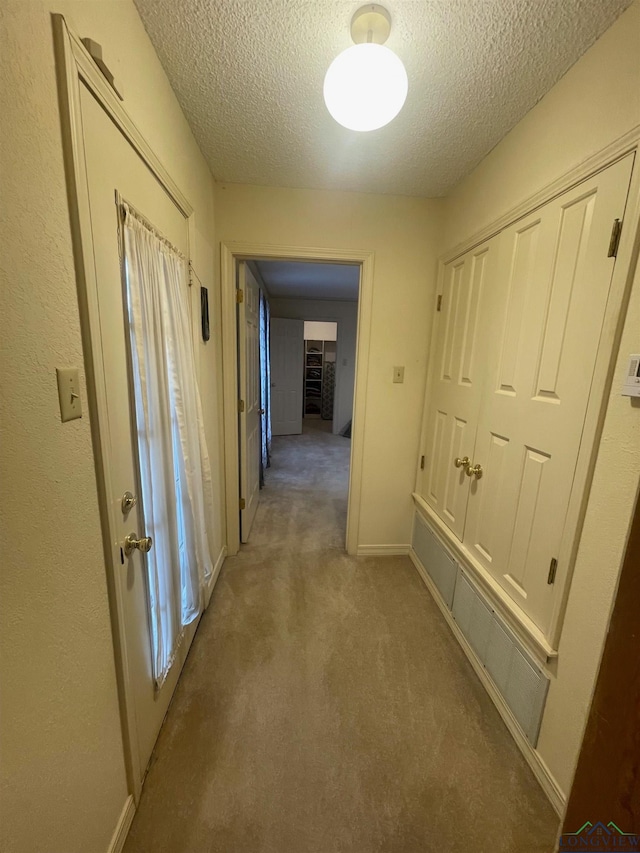 corridor featuring light colored carpet and a textured ceiling