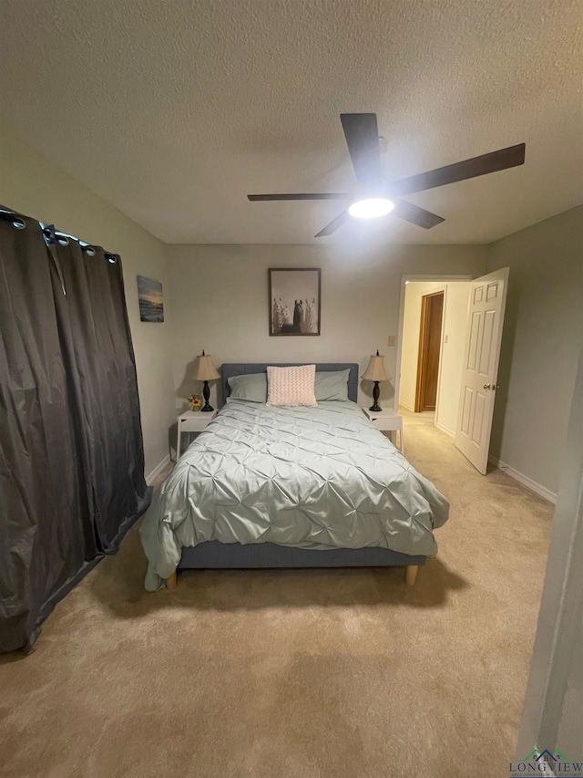 bedroom with ceiling fan, light colored carpet, and a textured ceiling