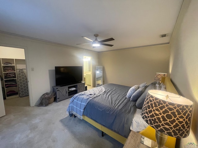 bedroom with a walk in closet, crown molding, a closet, and ceiling fan