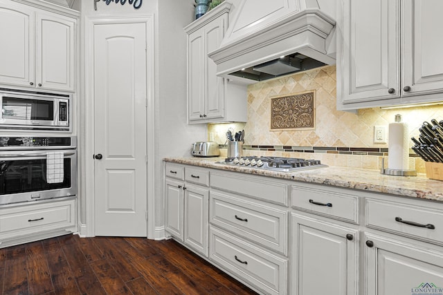 159 Jacobin Creek Dr, Gilmer, TX 75645 - kitchen with appliances with stainless steel finishes, custom range hood, white cabinetry, decorative backsplash, and dark wood finished floors