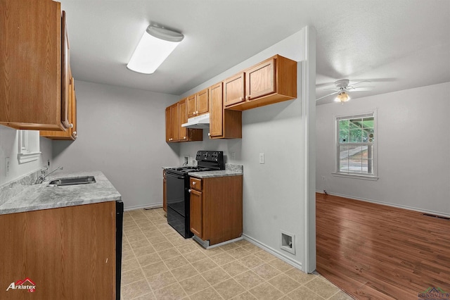 209 Norton Dr, Longview, TX 75602 - kitchen with electric range, under cabinet range hood, a sink, ceiling fan, and brown cabinets