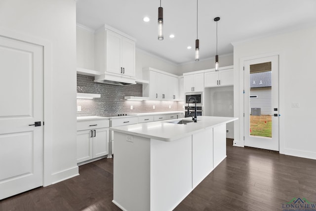 kitchen with stainless steel microwave, pendant lighting, white cabinets, and an island with sink