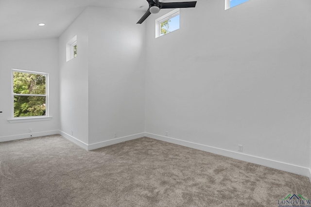 carpeted spare room with ceiling fan, a wealth of natural light, and high vaulted ceiling