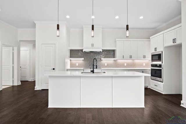 kitchen featuring stainless steel appliances, tasteful backsplash, sink, hanging light fixtures, and a kitchen island with sink