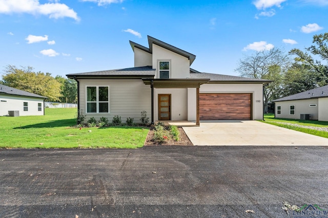 view of front facade with central AC, a garage, and a front yard