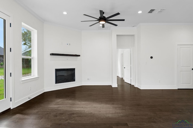 unfurnished living room featuring dark wood-type flooring, a wealth of natural light, and ornamental molding