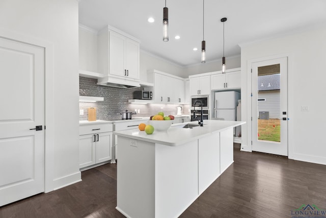 kitchen with pendant lighting, white cabinets, a center island with sink, and stainless steel microwave