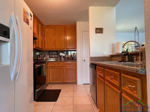 kitchen featuring range with electric cooktop, sink, stainless steel dishwasher, white refrigerator with ice dispenser, and light tile patterned floors