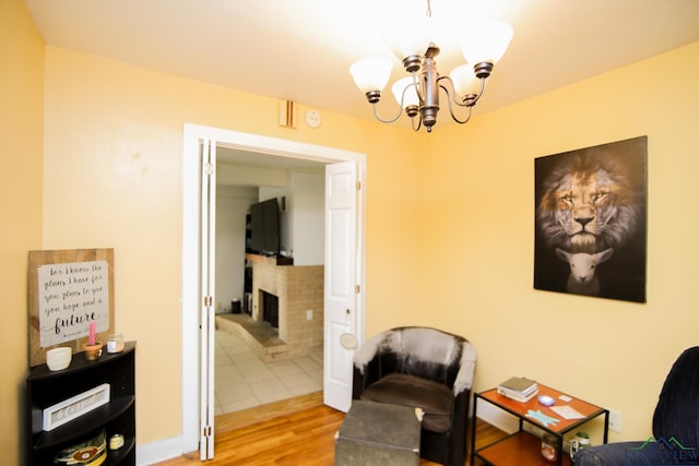 113 Fairview St, Marshall, TX 75672 - sitting room featuring wood finished floors, a chandelier, and a brick fireplace