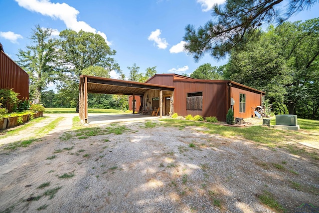 view of front of property with an attached carport, a pole building, driveway, and an outdoor structure