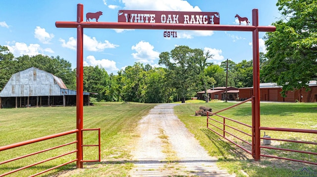 view of street with a rural view, driveway, a gated entry, and a barn