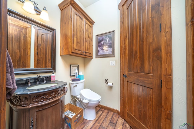 bathroom featuring vanity, wood finished floors, toilet, and baseboards