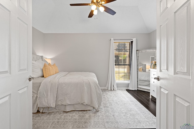 bedroom featuring ceiling fan, lofted ceiling, baseboards, and wood finished floors