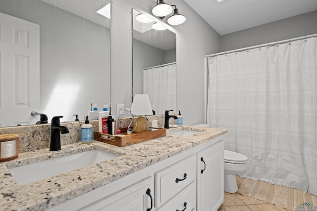bathroom featuring double vanity, toilet, tile patterned flooring, and a sink