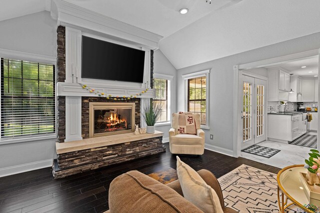living room featuring lofted ceiling, wood-type flooring, a stone fireplace, and plenty of natural light