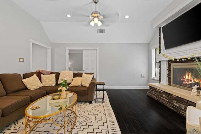 living room with lofted ceiling, a ceiling fan, visible vents, and a stone fireplace