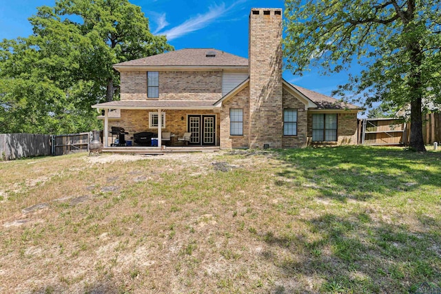 back of property with brick siding, a chimney, a lawn, and a fenced backyard