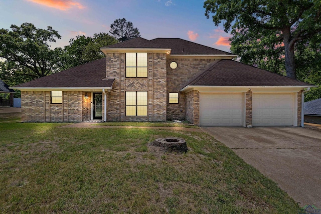 traditional home with an attached garage, a fire pit, brick siding, driveway, and a front lawn