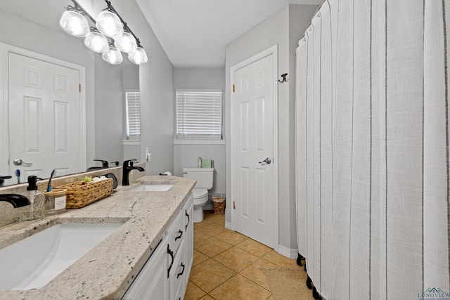 full bathroom with double vanity, tile patterned floors, toilet, and a sink