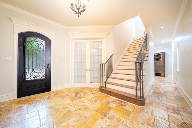 foyer entrance with crown molding, french doors, and a chandelier