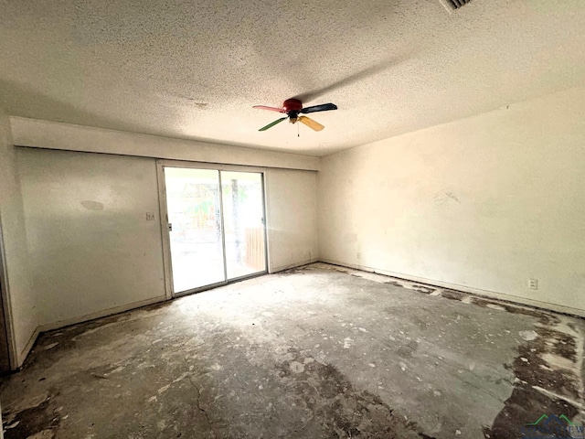 unfurnished room with ceiling fan and a textured ceiling