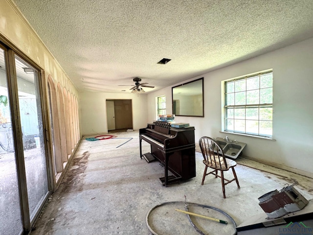 miscellaneous room featuring ceiling fan and a textured ceiling