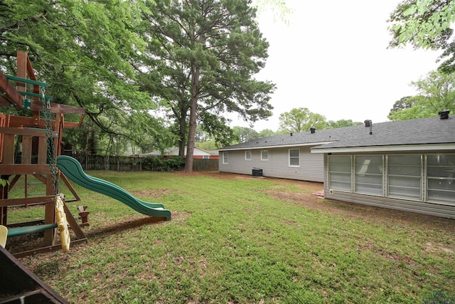 view of yard with central AC, fence, and a playground