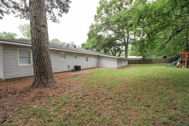 view of yard featuring a playground, fence private yard, and central AC