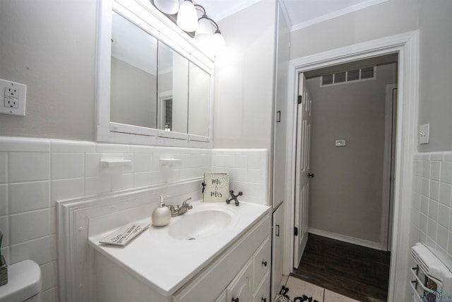 bathroom featuring visible vents, toilet, tile walls, vanity, and wainscoting