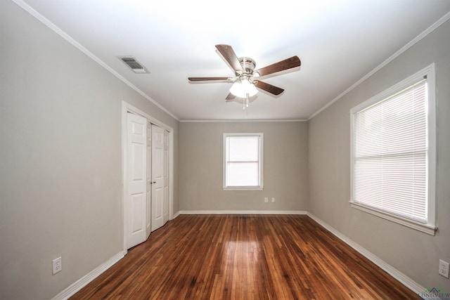 unfurnished bedroom featuring dark wood-type flooring, crown molding, baseboards, and visible vents