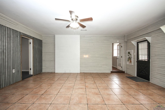 interior space featuring visible vents, light tile patterned floors, ceiling fan, and brick wall