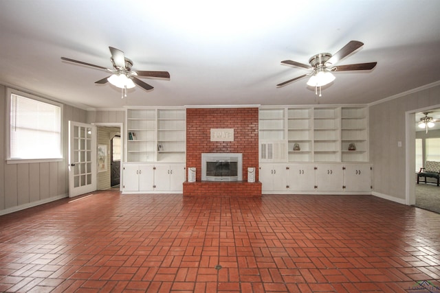 unfurnished living room featuring a fireplace, brick floor, a ceiling fan, and ornamental molding