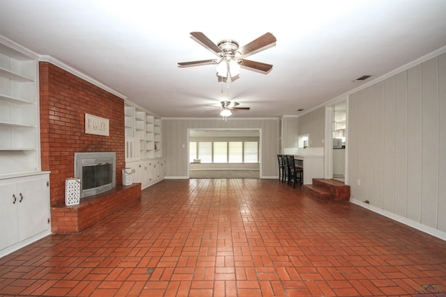 unfurnished living room with crown molding, a fireplace, a ceiling fan, and brick floor