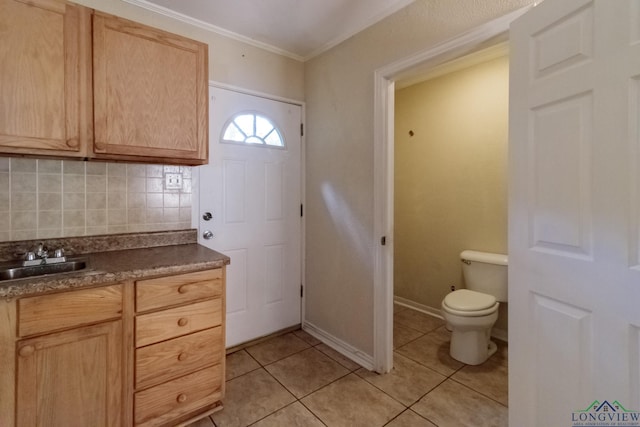 interior space featuring crown molding, vanity, toilet, tile patterned floors, and decorative backsplash