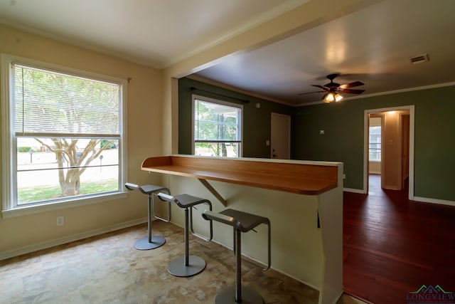 kitchen featuring baseboards, ornamental molding, a breakfast bar, and visible vents