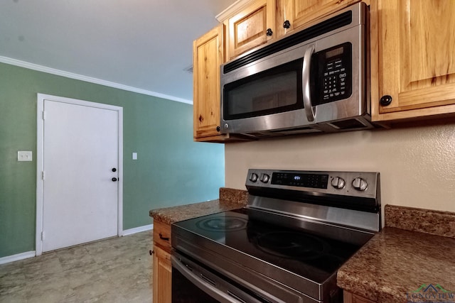 kitchen with dark countertops, appliances with stainless steel finishes, ornamental molding, and baseboards
