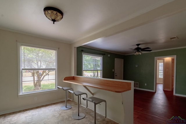 1321 Lake Dr, Longview, TX 75601 - kitchen featuring crown molding, healthy amount of natural light, baseboards, a kitchen bar, and a peninsula