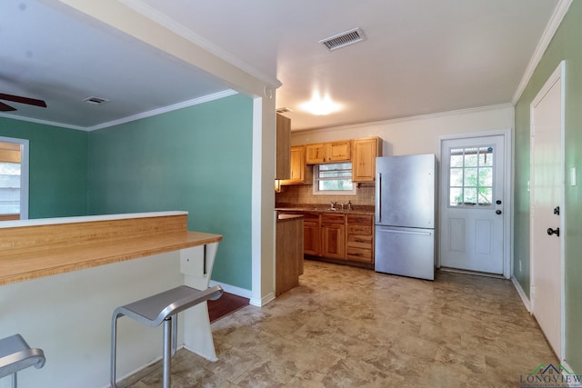 1321 Lake Dr, Longview, TX 75601 - kitchen featuring freestanding refrigerator, a ceiling fan, crown molding, decorative backsplash, and baseboards