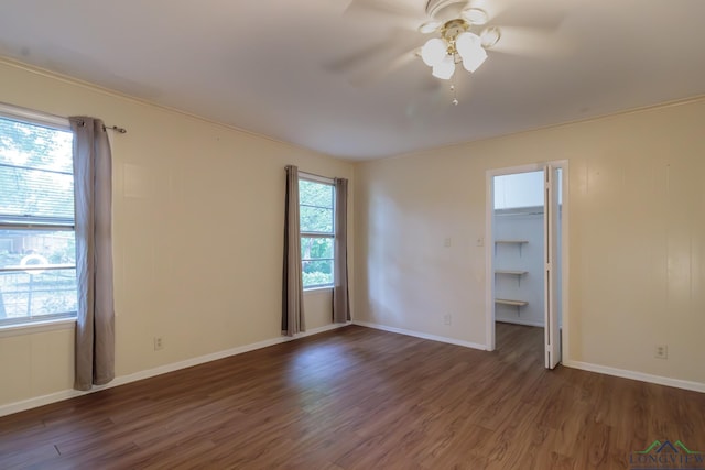 1321 Lake Dr, Longview, TX 75601 - unfurnished bedroom featuring wood finished floors, a spacious closet, baseboards, and a ceiling fan