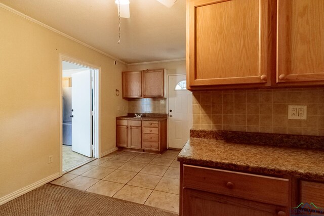 kitchen featuring ornamental molding, tasteful backsplash, light tile patterned floors, baseboards, and a ceiling fan