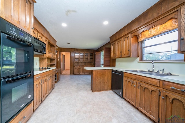 107 Tulip St, White Oak, TX 75693 - kitchen featuring a sink, a peninsula, light countertops, brown cabinets, and black appliances