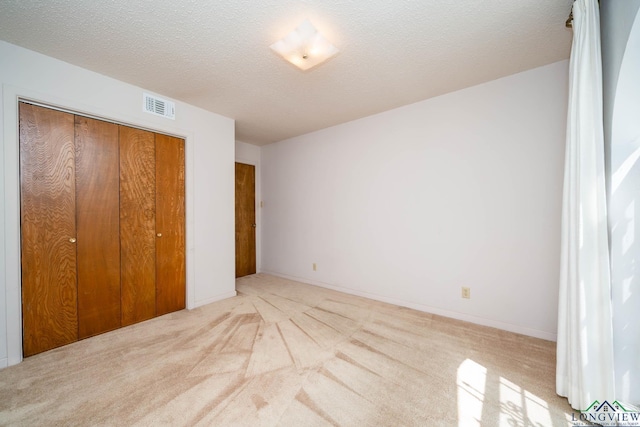 107 Tulip St, White Oak, TX 75693 - unfurnished bedroom featuring visible vents, a textured ceiling, carpet flooring, and a closet