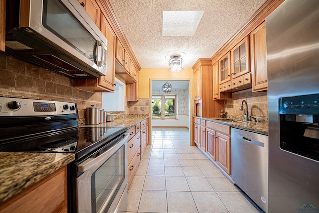 kitchen with a skylight, light tile patterned floors, stainless steel appliances, and stone countertops