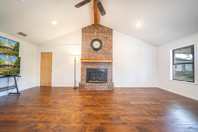 unfurnished living room featuring a wood stove, ceiling fan, dark wood-type flooring, lofted ceiling with beams, and a textured ceiling