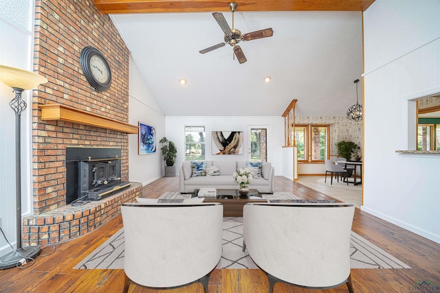 living room with light wood-type flooring, lofted ceiling with beams, plenty of natural light, and ceiling fan