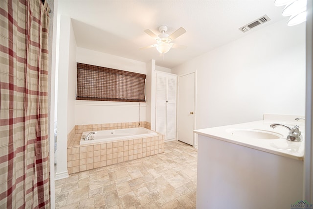 bathroom with vanity, a relaxing tiled tub, and ceiling fan