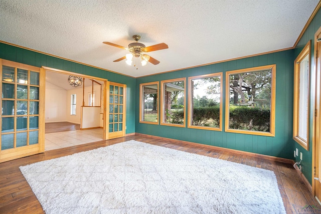 unfurnished room featuring french doors, crown molding, hardwood / wood-style floors, a textured ceiling, and ceiling fan with notable chandelier