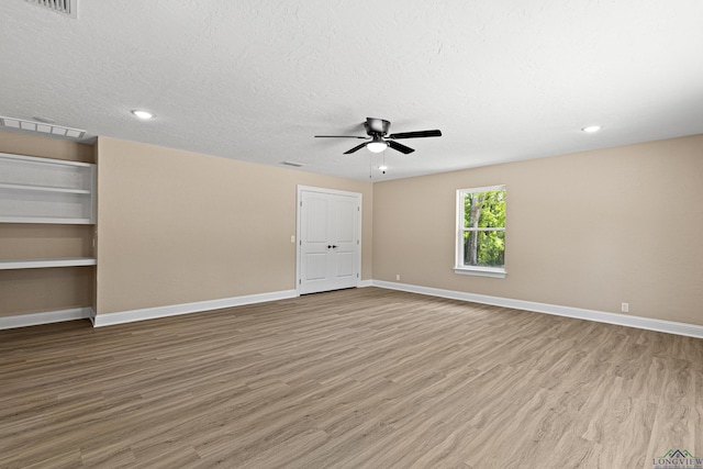 empty room featuring baseboards, ceiling fan, a textured ceiling, and light wood-style floors